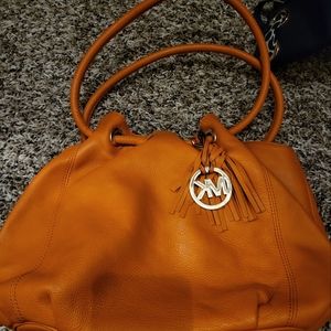 An orange michael kirs purse